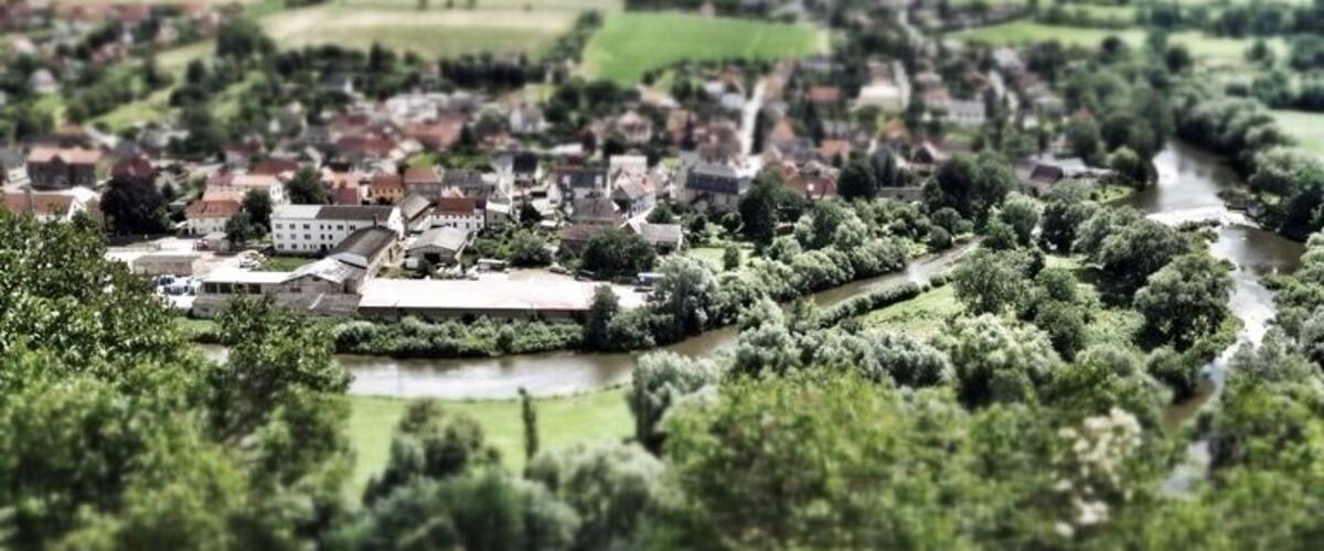 A model of a town with a river, surrounded by greenery and hills.