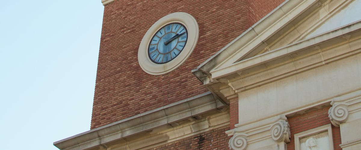 A clock tower with a weather vane on top.