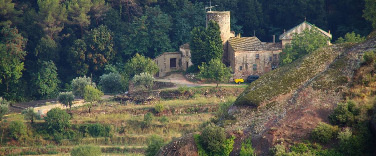A rural landscape with a stone tower, traditional buildings, and terraced fields.