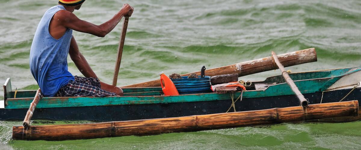 A man paddling a traditional wooden boat on a body of water.