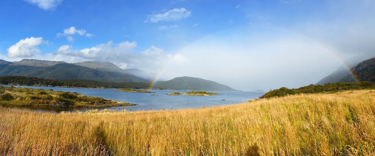 A lake with islands, mountains, and a rainbow.