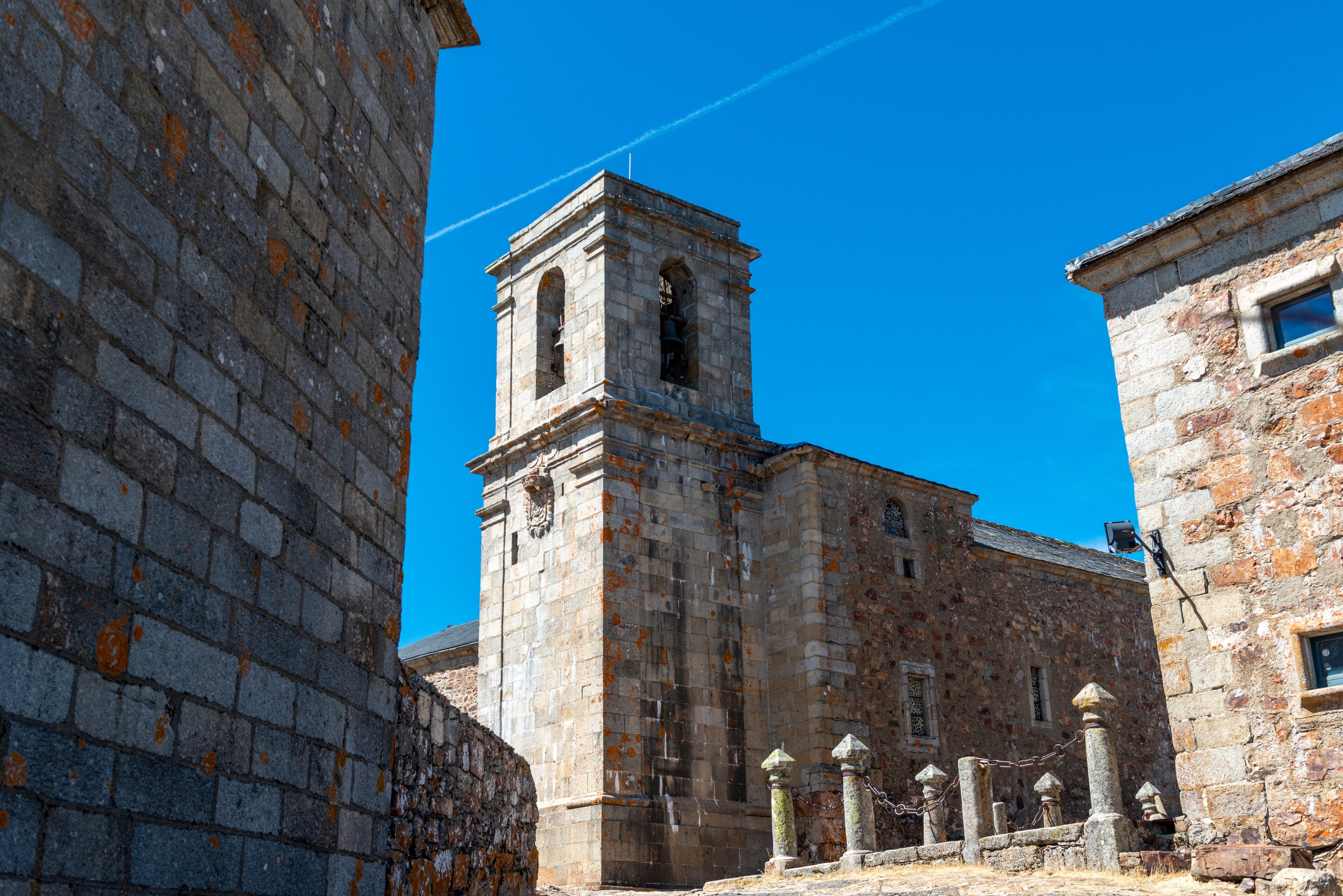A historic stone building with a bell tower, surrounded by other stone structures.