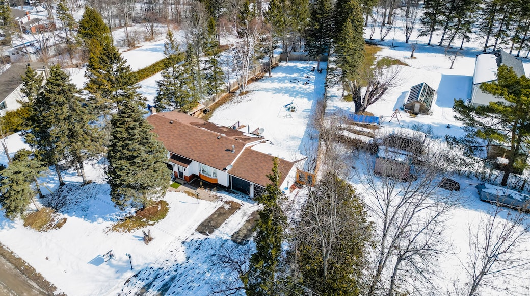 Residential property showcasing a house with an attached garage, surrounded by evergreen trees and snow covered ground along glen cedar drive, ramara, simcoe county, ontario, canada