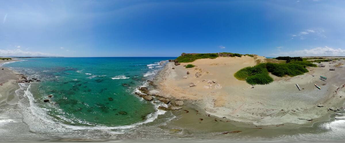A coastal landscape with clear turquoise waters, sandy beaches, and green vegetation on a cliff.