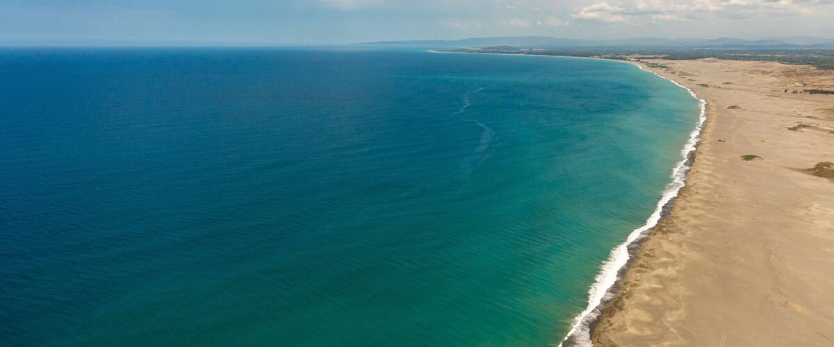 Un paisaje costero con una playa arenosa y un océano azul cristalino.