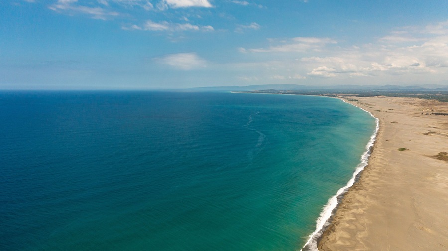 Un paisaje costero con una playa arenosa y un océano azul cristalino.