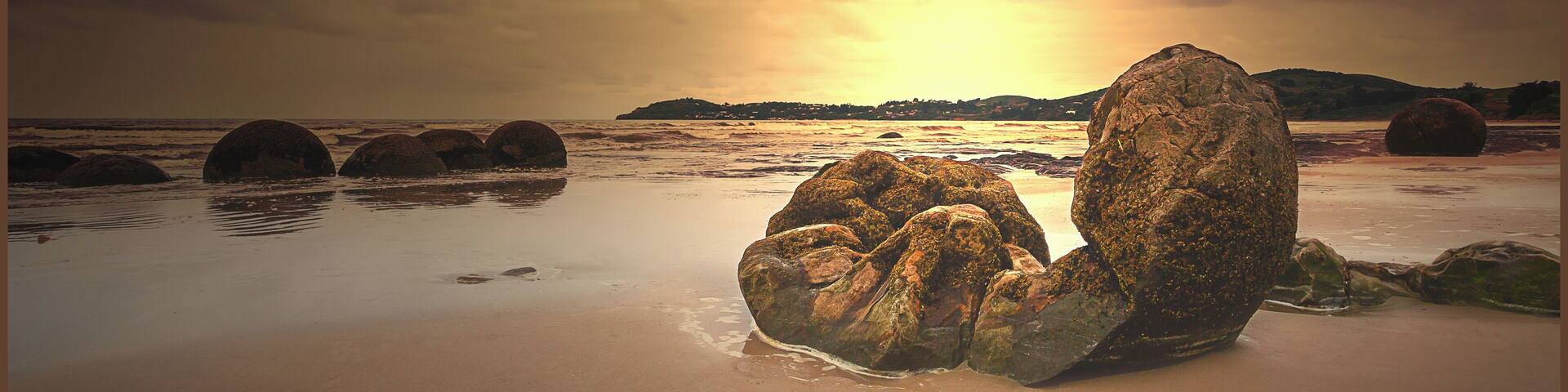 A beach with large rocks and a sunset.