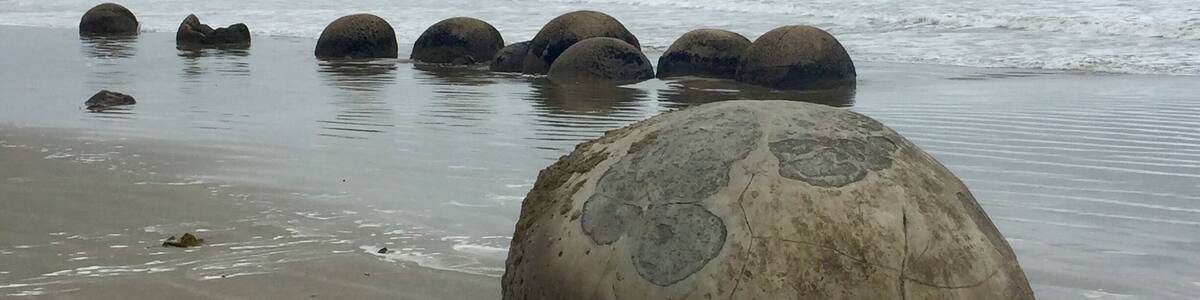 A beach with large boulders and a cloudy sky.