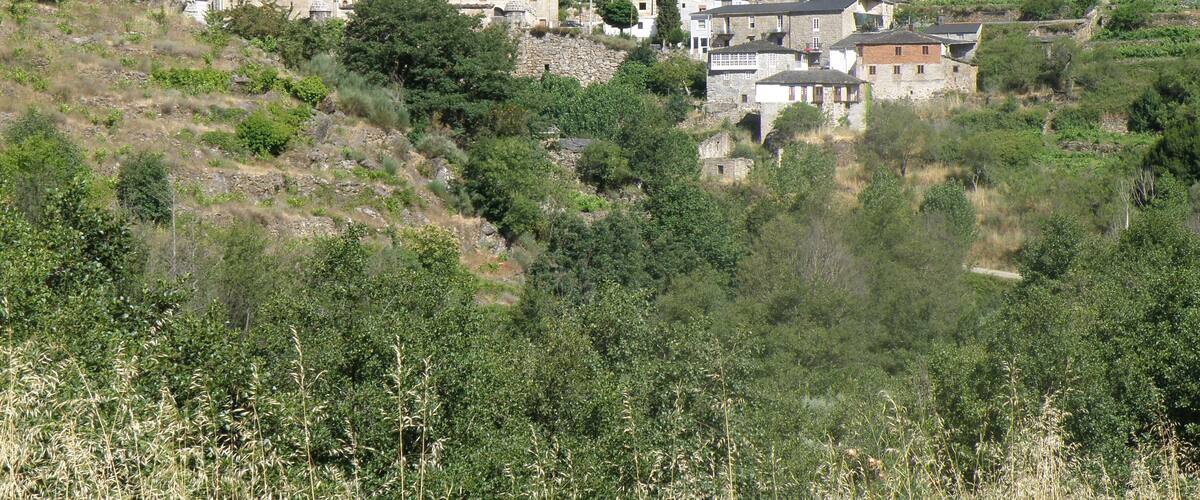 A hillside village with stone buildings and lush greenery.