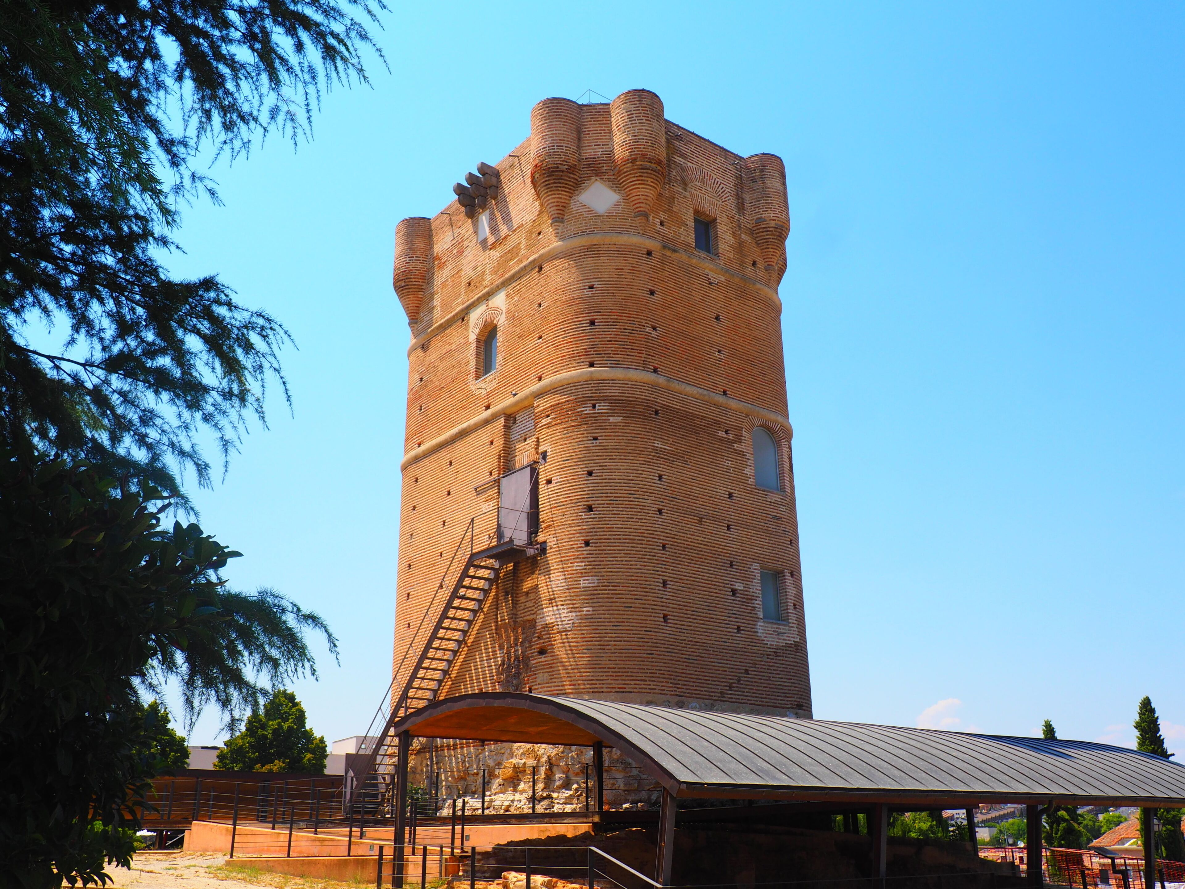 A tall brick tower with a spiral staircase and a covered viewing platform.