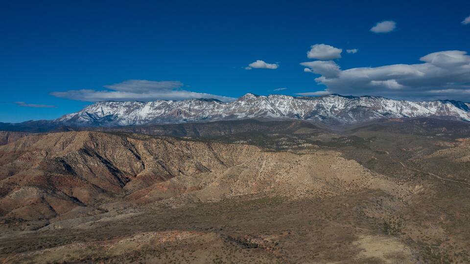A mountain range with snow-capped peaks and a clear blue sky.