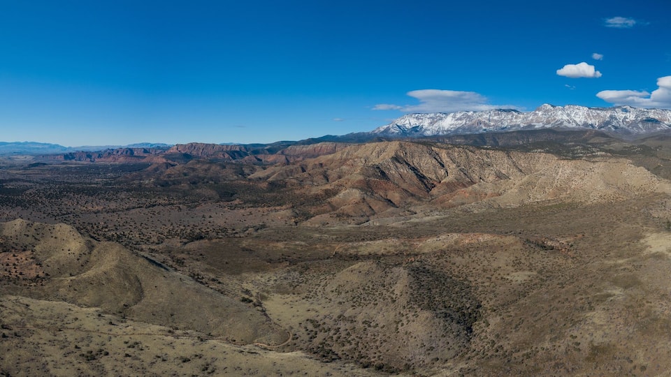 A mountainous landscape with a highway and snow-capped peaks in the distance.