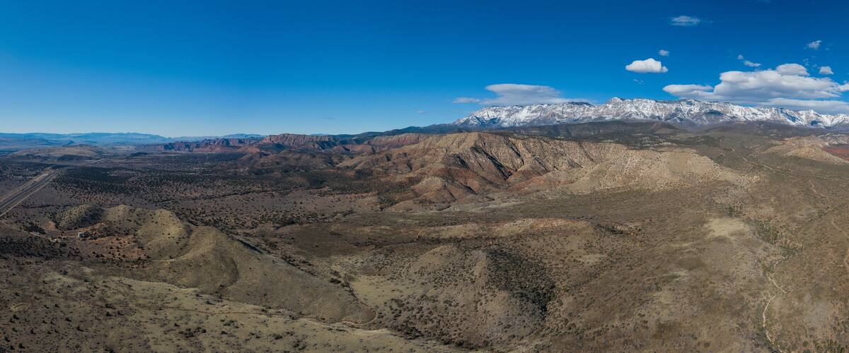 A mountainous landscape with a highway and snow-capped peaks in the distance.