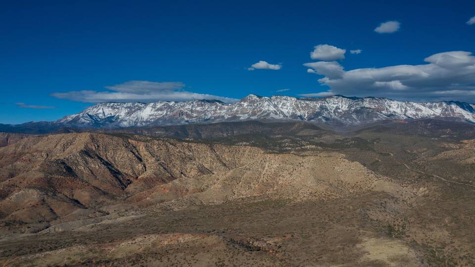 A mountain range with snow-capped peaks and a clear blue sky.