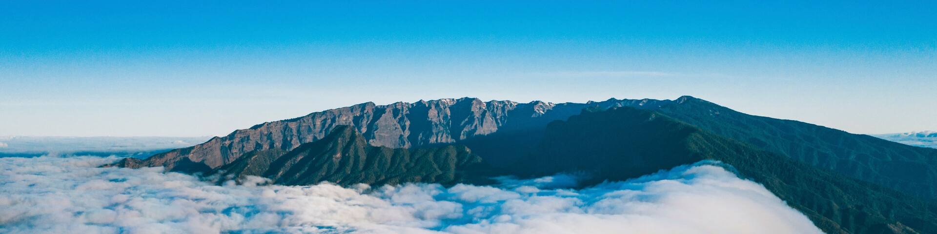 A mountain range with a cloud-covered peak and forested slopes.