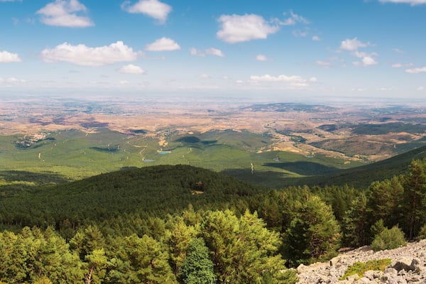Un paysage montagneux caractérisé par de vastes forêts, un terrain rocheux et un ciel dégagé.
