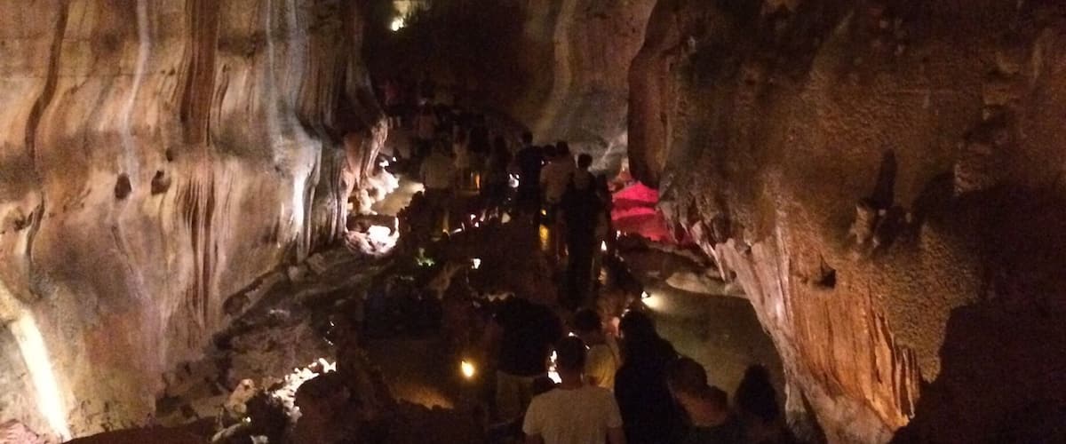 A cave with stalactites and stalagmites, illuminated by artificial lights.