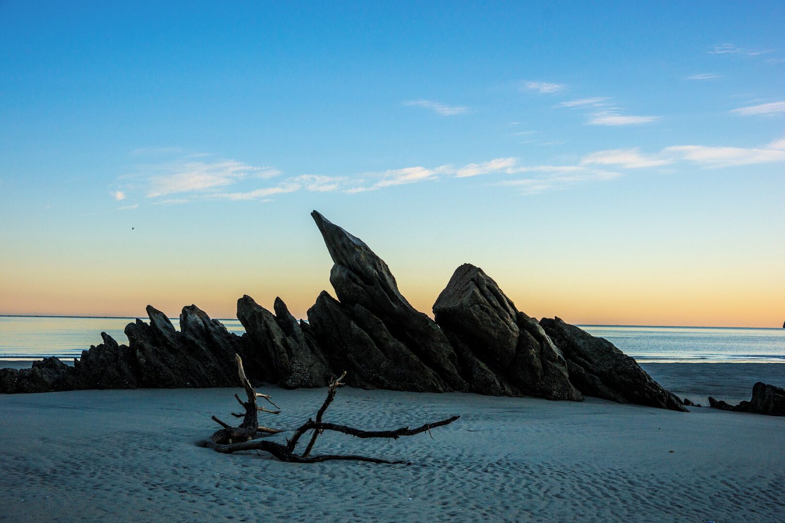 A rocky coastline with a prominent rock formation at sunset.