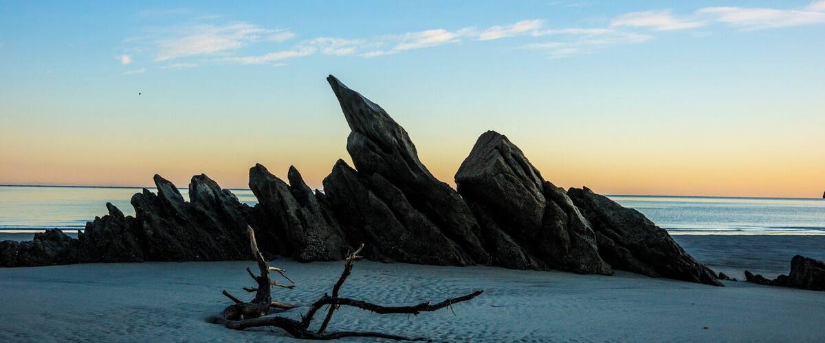 A rocky coastline with a prominent rock formation at sunset.