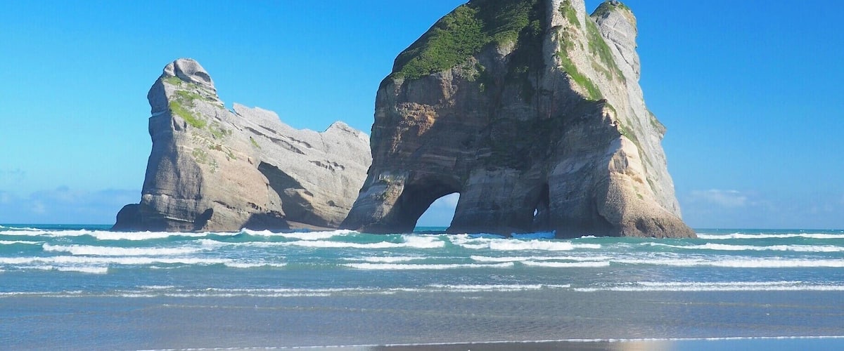 Eine große Felsformation mit einem natürlichen Bogen über dem Meer.