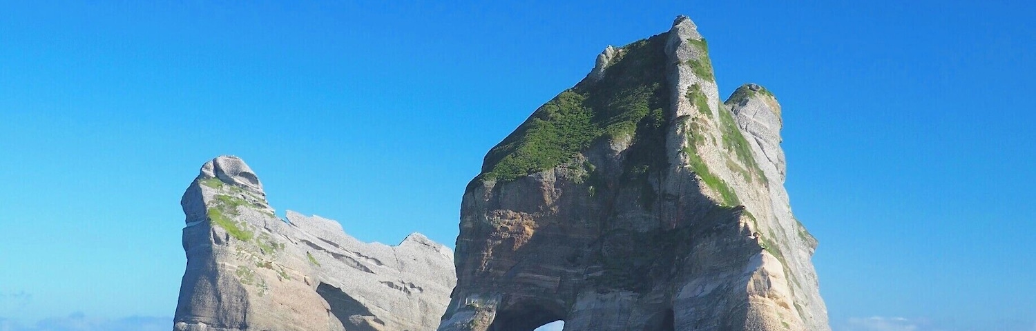 Eine große Felsformation mit einem natürlichen Bogen über dem Meer.