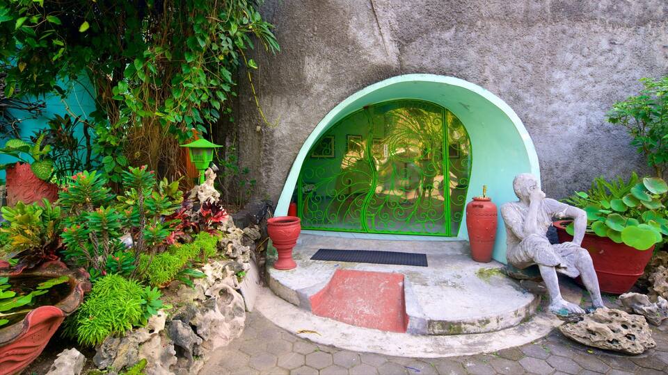 A garden with a green door, a stone statue, and various plants.
