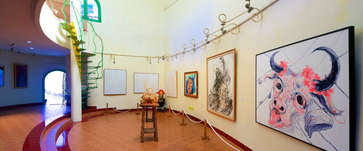 An art gallery with various paintings, a spiral staircase, and a large bull painting.