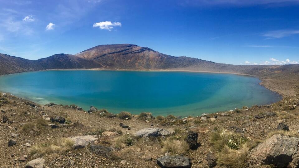 A large, turquoise lake surrounded by rocky hills and sparse vegetation.
