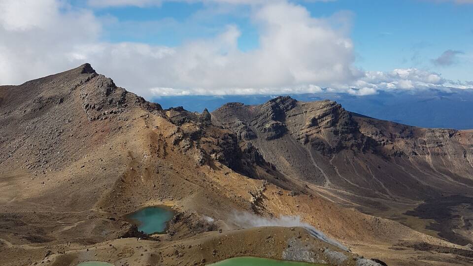 A mountainous landscape with green lakes and a clear sky.