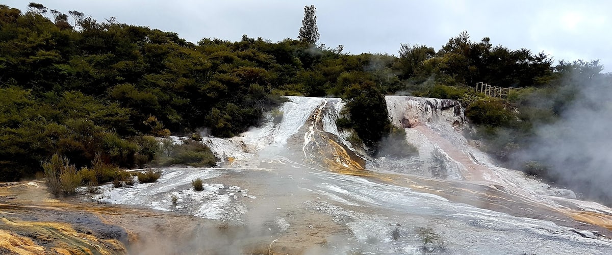 A geothermal area with a hot spring, steam, and mineral deposits.