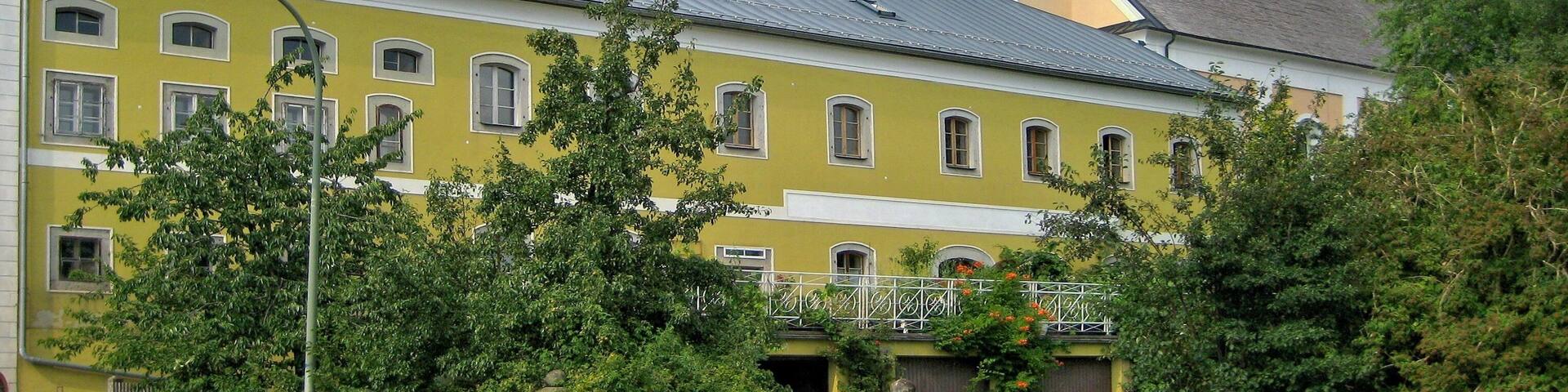 Breitenberg, historic grocery store with Parish Church of St Raymond of Peñafort in background.