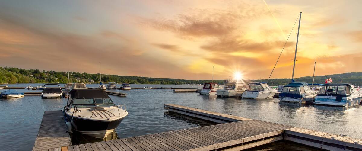 A marina with boats docked at wooden piers during sunset.