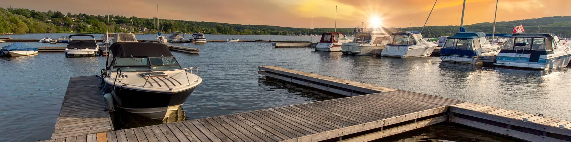 A marina with boats docked at wooden piers during sunset.