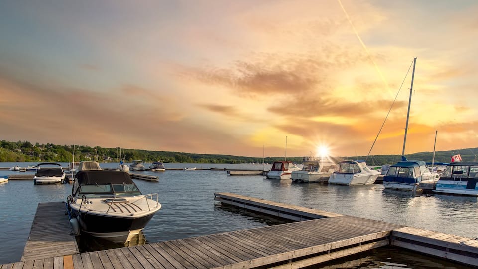 A marina with boats docked at wooden piers during sunset.