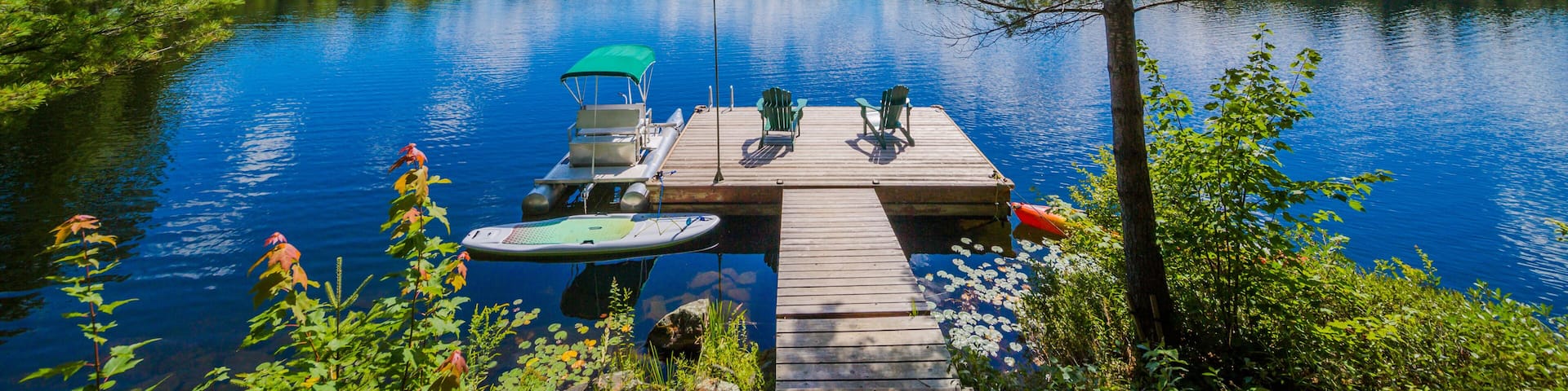 Two Ontario chairs sitting on a wood dock facing a calm lake.