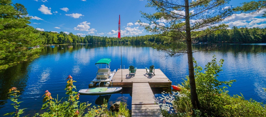 Two Ontario chairs sitting on a wood dock facing a calm lake.