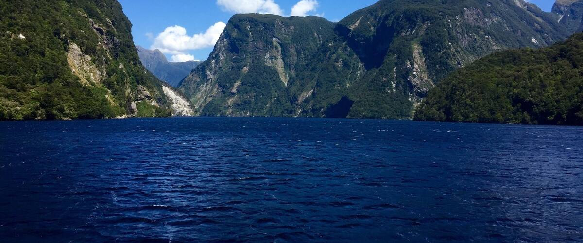 A deep blue sea with a mountainous landscape in the background.