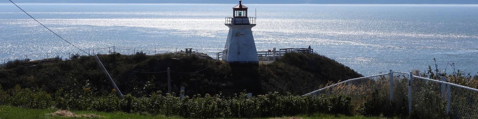Un faro en una colina cubierta de hierba con vista al mar.