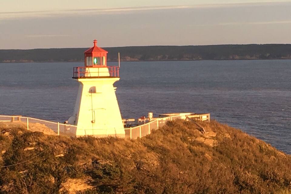 A lighthouse on a rocky outcrop by the sea.