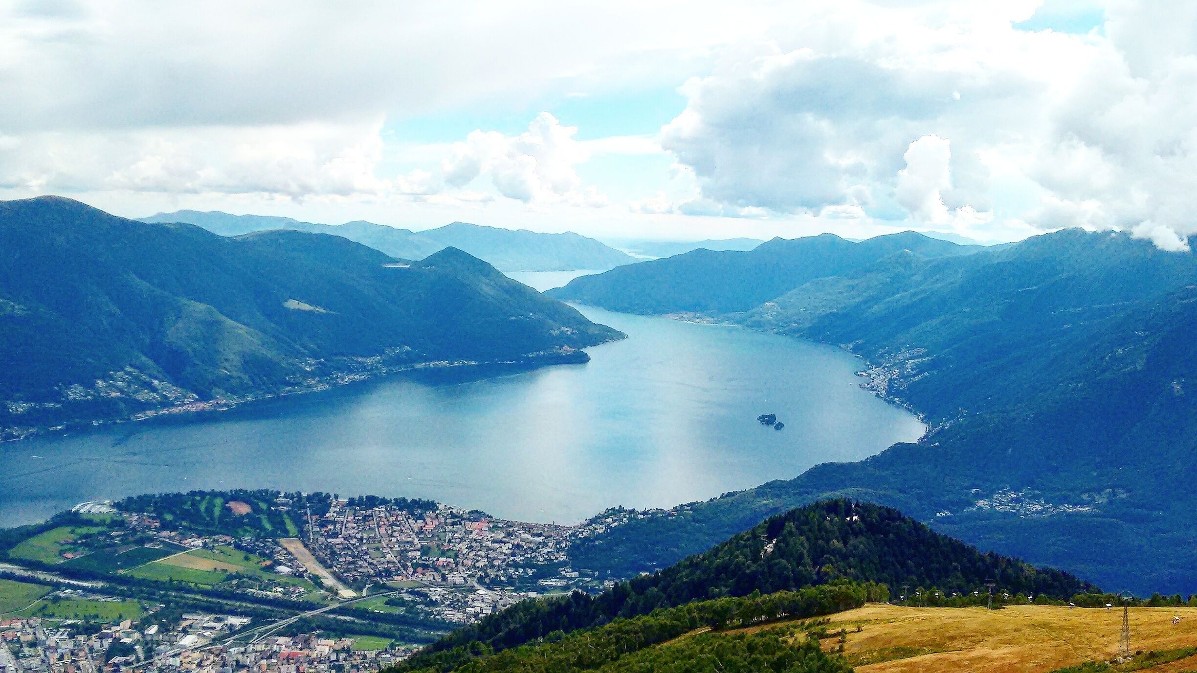 A lake surrounded by mountains, a town in the foreground, and a clear sky.