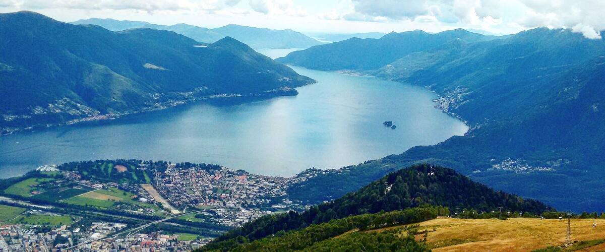 A lake surrounded by mountains, a town in the foreground, and a clear sky.