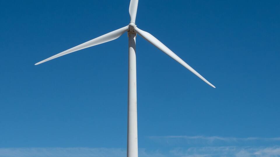 A large wind turbine in a field with a clear blue sky.