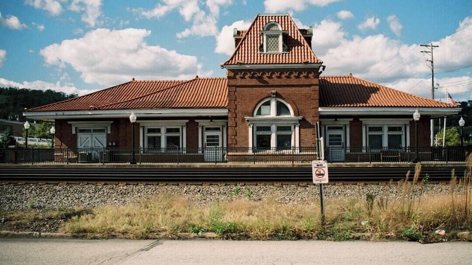 A brick train station with a red roof and a clock tower.