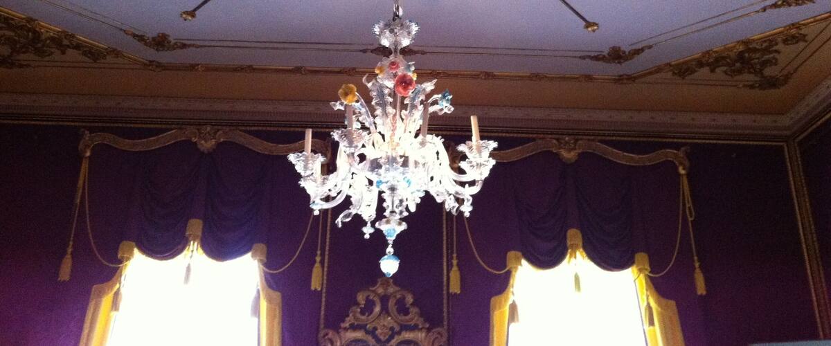 A chandelier with a central ornate design and multiple arms, hanging from a ceiling with a sunburst pattern.
