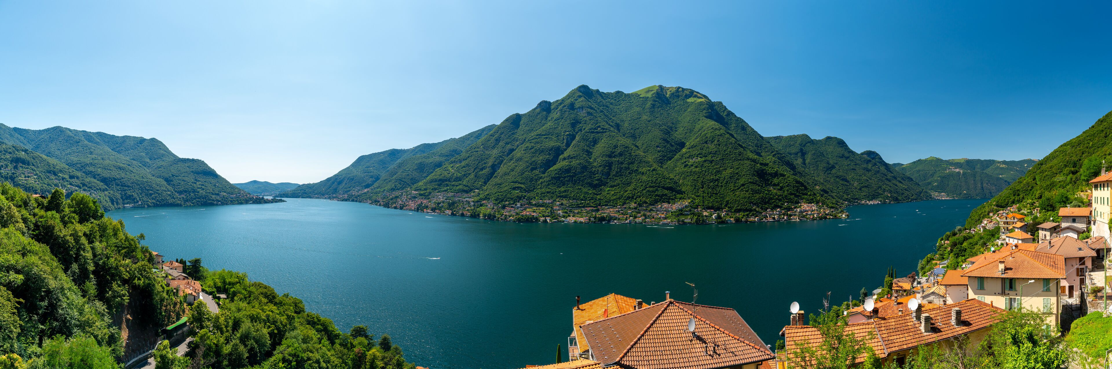 A lake surrounded by mountains, with houses on the right side.