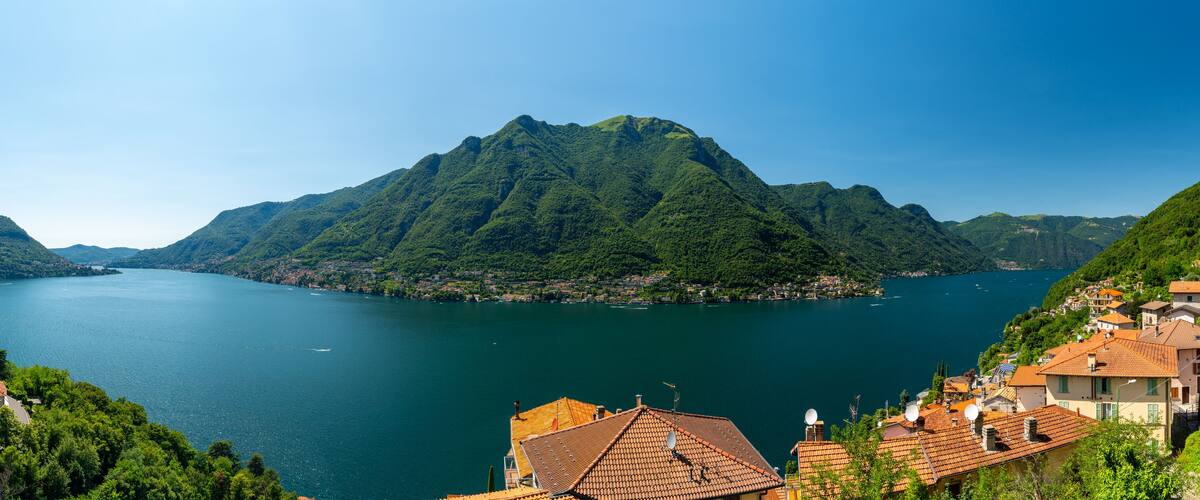 A lake surrounded by mountains, with houses on the right side.