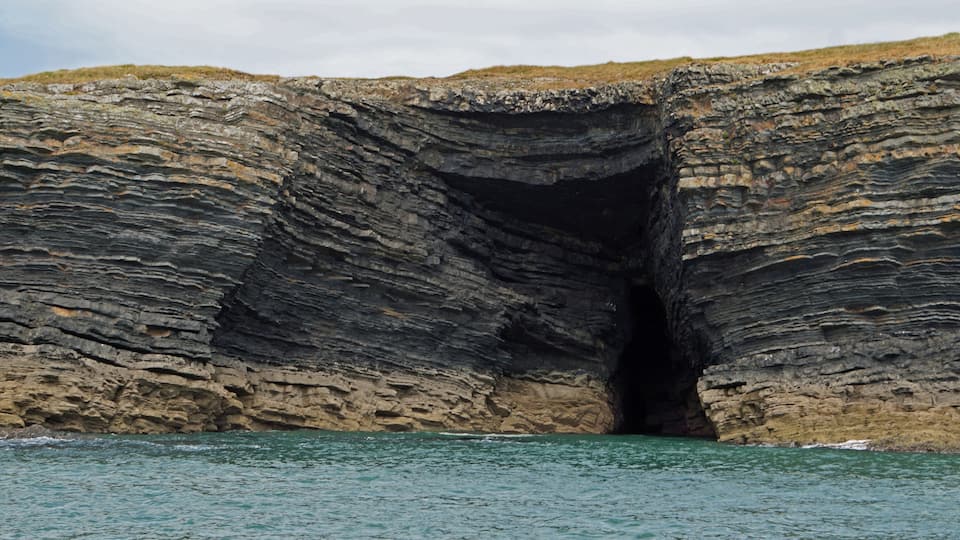 A large rock formation with a cave entrance.
