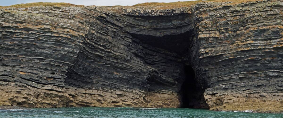 A large rock formation with a cave entrance.