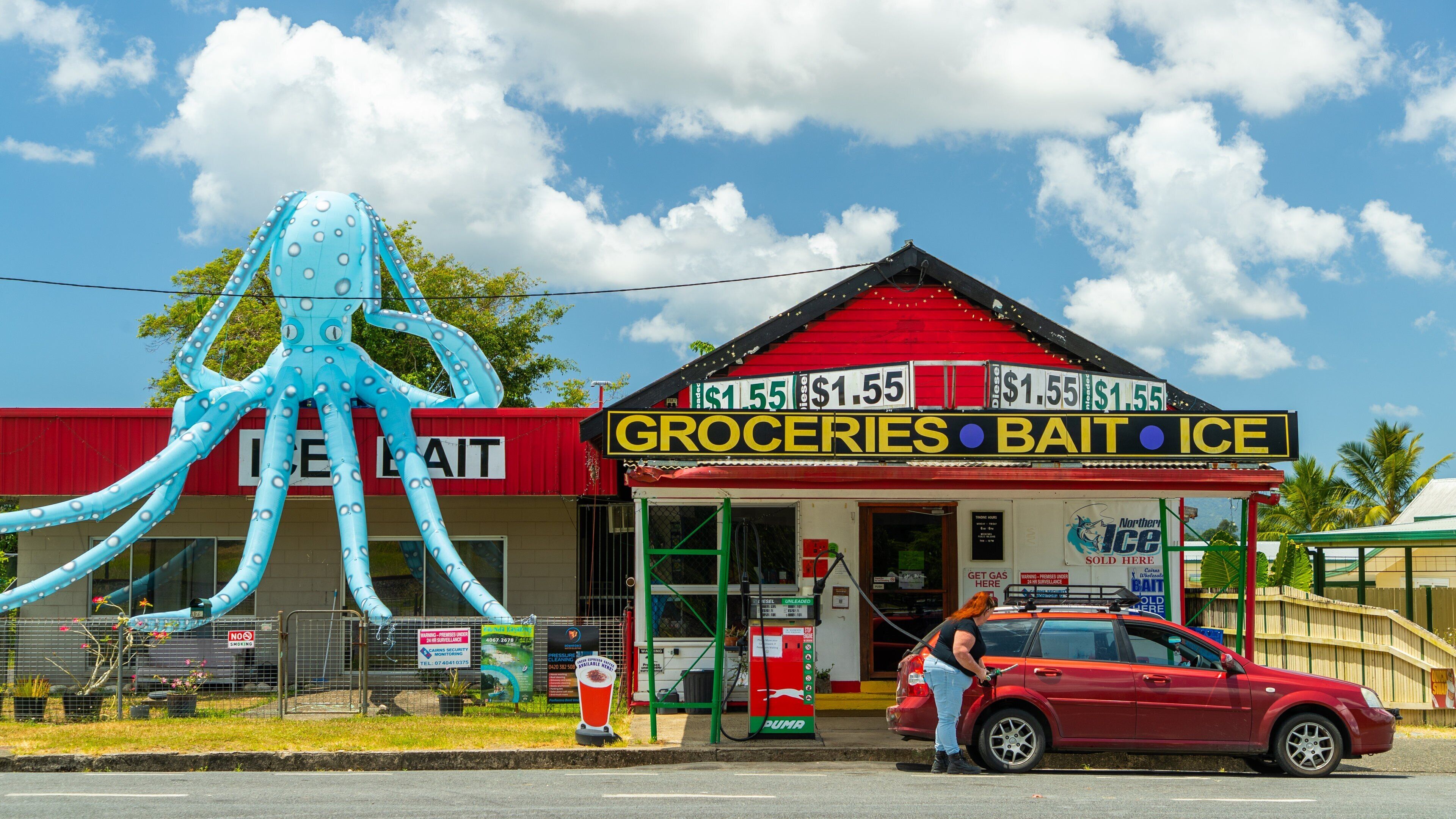 A store named 'Groceries Bait Ice' with a large inflatable octopus outside.