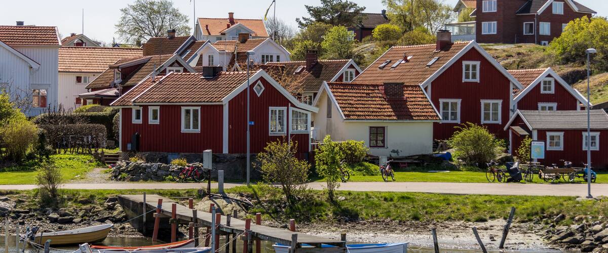 A coastal village with traditional red houses, a wooden pier, and boats docked at the shore.